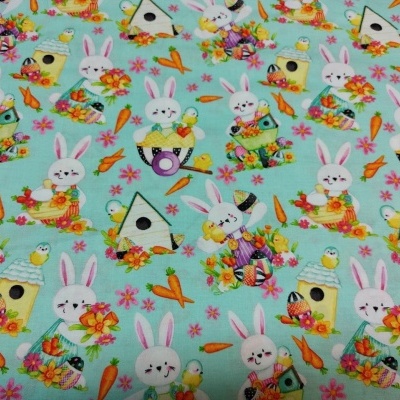 tecido azul turquesa com padrão de coelhos, ovos, flores, cenouras, passarinhos e casinhas