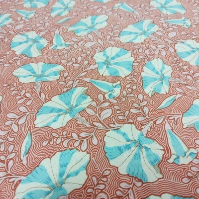 Tecido floral azul e branco sobre fundo castanho com padrão ondulado.