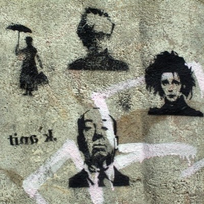 Grafite preto com retratos estilizados e figura feminina com guarda-chuva numa parede rugosa