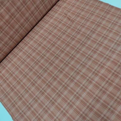 Tecido xadrez castanho e bege enrolado sobre superfície azul