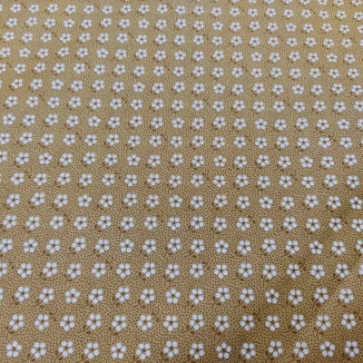 tecido bege com pequenas flores brancas em padrão uniforme