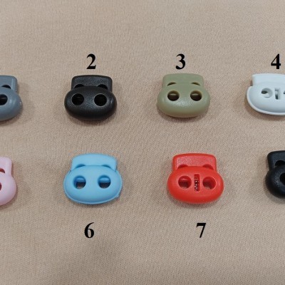 Oito reguladores coloridos para cordão numerados e um com texto sobre fundo bege.