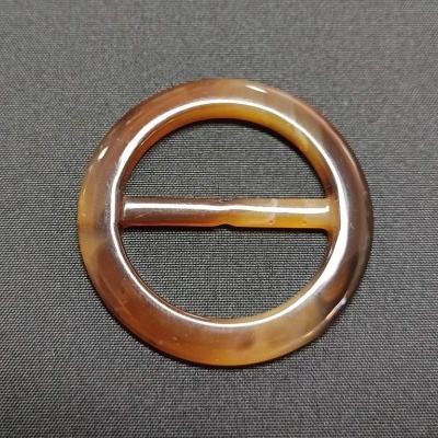 fivela redonda em resina marmoreada castanha sobre fundo preto