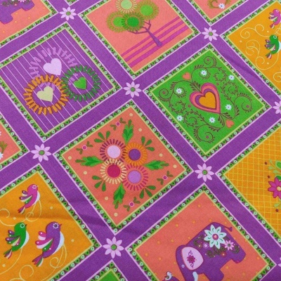 Tecido colorido com padrões de corações, flores, pássaros e elefantes formando uma grade