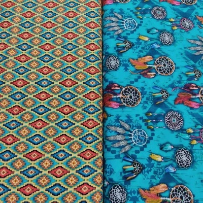 Dois tecidos dobrados com padrões coloridos, um com padrão geométrico e outro com apanhadores de sonhos sobre fundo azul turquesa