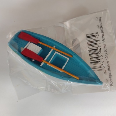 Miniatura de barco azul com remos vermelhos e amarelos em embalagem plástica transparente