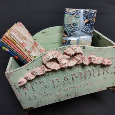 Caixa de madeira verde envelhecido com tecidos coloridos e padrão em relevo cor-de-rosa