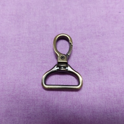 Mosquetão de metal bronze sobre tecido lilás