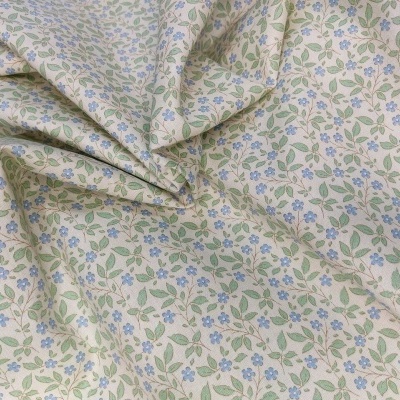 Tecido de algodão com padrão floral azul e verde sobre fundo bege