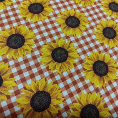 Tecido com estampa de girassóis sobre padrão xadrez castanho e branco
