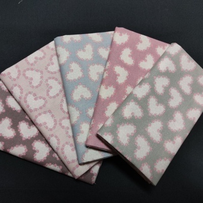 Tecidos com padrão de corações em tons pastel sobre fundo preto