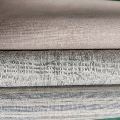 Três tecidos dobrados com riscas em tons de rosa, cinza e branco