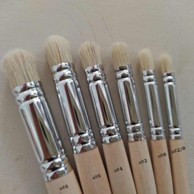 Sete pincéis com cabos de madeira clara e cerdas brancas