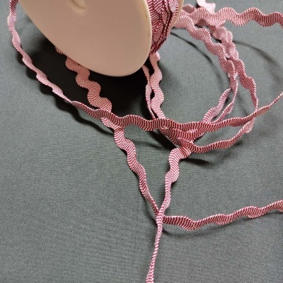 Fita decorativa rosa ondulada sobre superfície cinza
