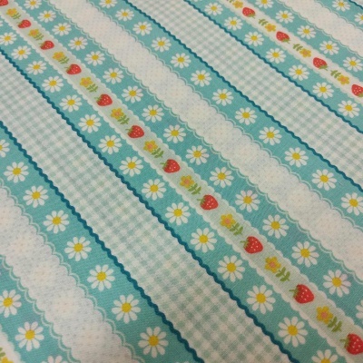 Tecido azul com padrão de margaridas, morangos e listas em riscas horizontais
