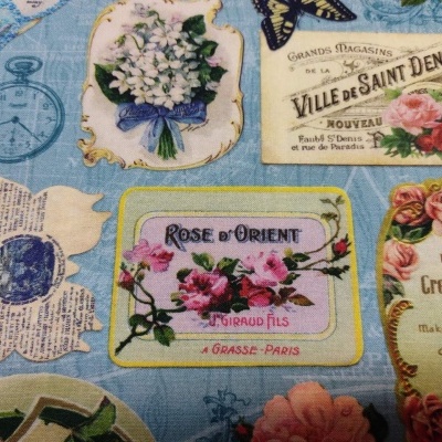 tecido azul claro com estampas florais e etiquetas vintage coloridas