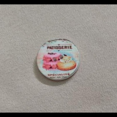 Botão decorativo redondo com imagem de macarons e texto em francês