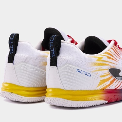Sapatilhas desportivas brancas com detalhes amarelos e vermelhos, sola branca, palavra TACTICO no calcanhar.