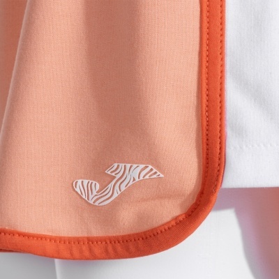 Detalhe de tecido cor de salmão com borda alaranjada e logótipo J branco com padrão de zebra