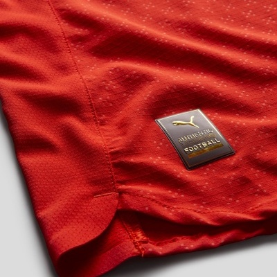 Detalhe de tecido vermelho com etiqueta Puma AUTHENTIC FOOTBALL