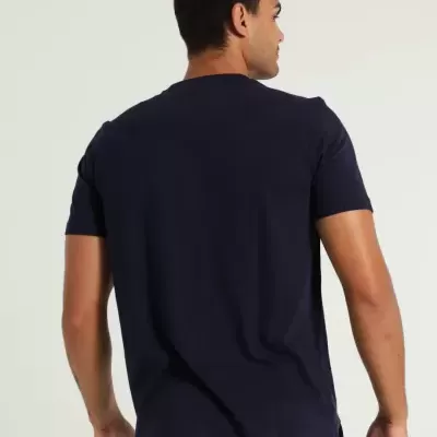 Homem de costas a usar t-shirt azul escura de manga curta