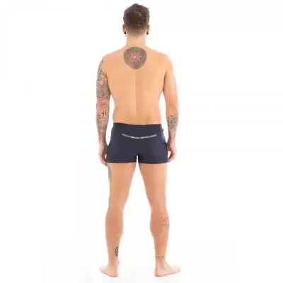 Vista traseira de homem com calções de banho pretos e texto branco no cós
