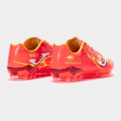 Par de chuteiras de futebol laranja com detalhes amarelos e logo Joma