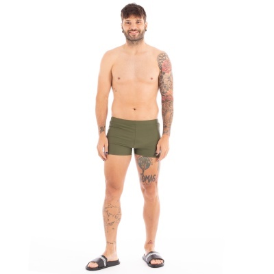 Homem com calções de banho verdes oliva e sandálias pretas em fundo branco