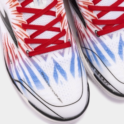 Tênis brancos com padrões vermelhos e azuis, atacadores vermelhos e detalhes pretos