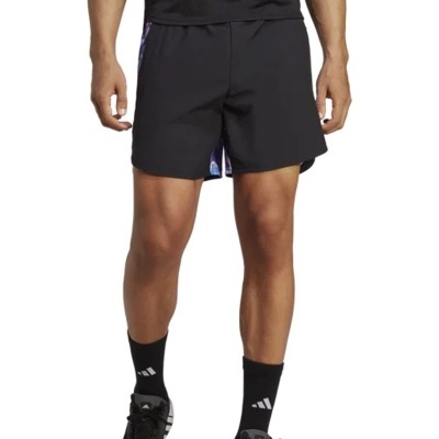 Calções pretos com faixa lateral multicolorida usados com meias e ténis pretos Adidas