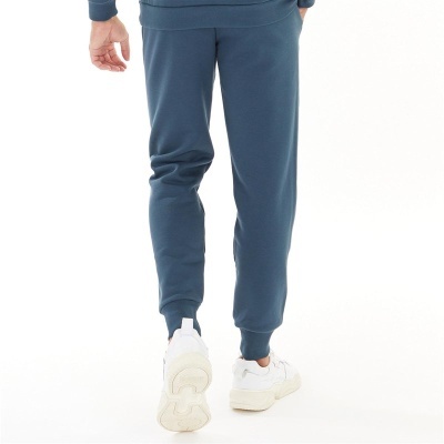 Calças de treino azuis com bainhas elásticas usadas com ténis brancos