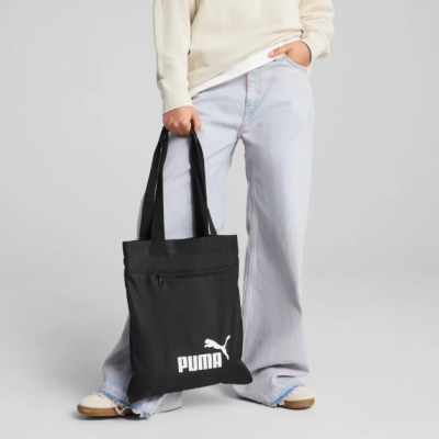 Saco preto Puma com logo branco usado por pessoa com calças azuis largas
