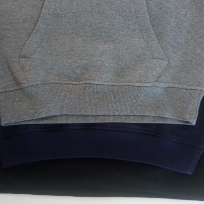 Três sweatshirts em tons cinza, azul escuro e preto empilhadas