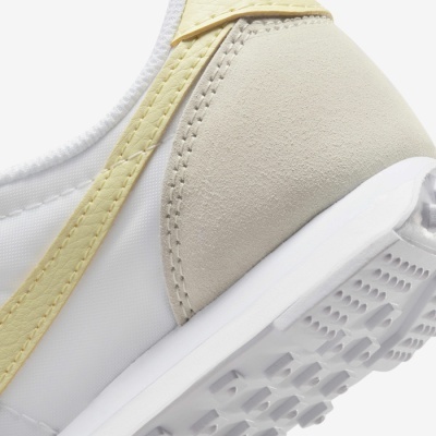 Parte traseira de ténis branco e bege com sola texturada e faixa amarela