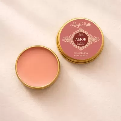 Lata dourada aberta com bálsamo labial rosa, rótulo Amor da Magic Bath, fundo claro texturado