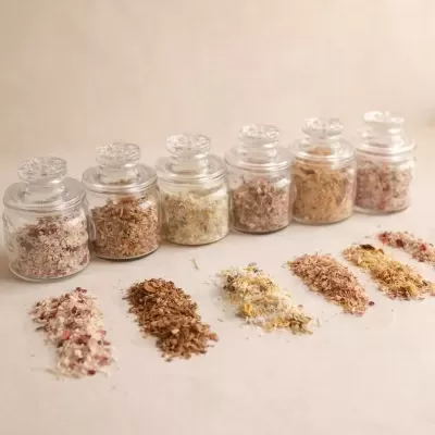 Frascos de vidro com misturas de ervas e pétalas coloridas