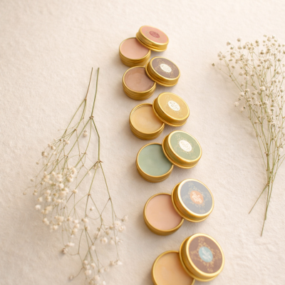 Conjunto de frascos dourados com cosméticos e flores brancas ao lado