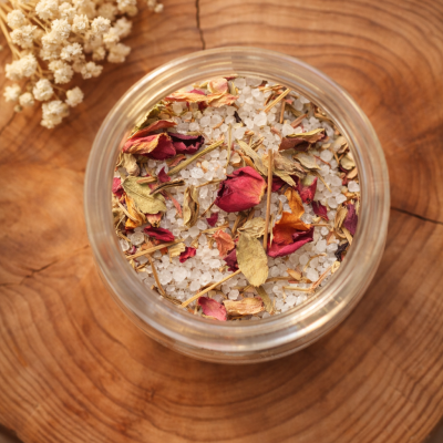 Frasco com sal grosso e pétalas secas sobre base de madeira