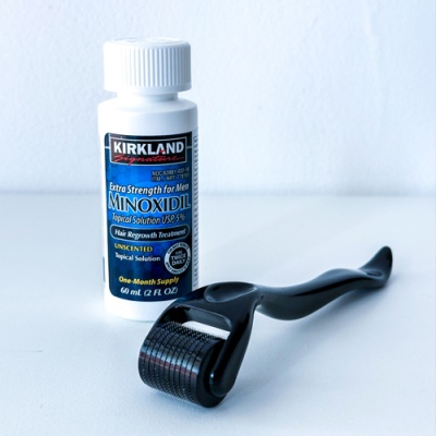 Frasco de Minoxidil e rolo de microagulhas preto