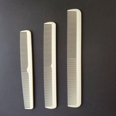 Três pentes brancos de vários tamanhos sobre fundo preto