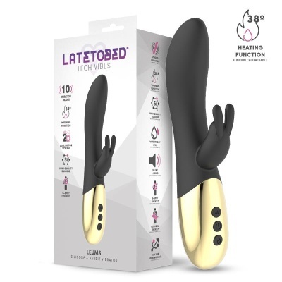 Vibrador de silicone preto com base dourada e três botões pretos ao lado da caixa branca com o produto e texto