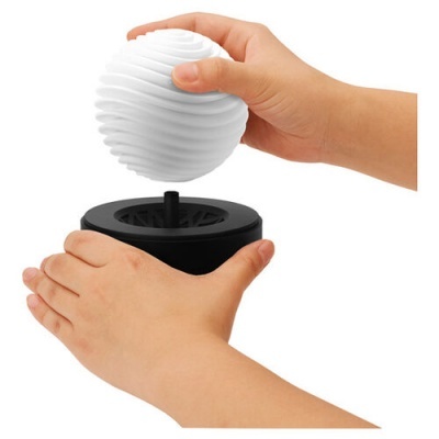 Mãos segurando esfera branca com textura ondulada sobre base preta