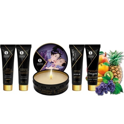 Conjunto de produtos Shunga com tubos pretos, vela acesa com tampa ilustrada e fruta tropical