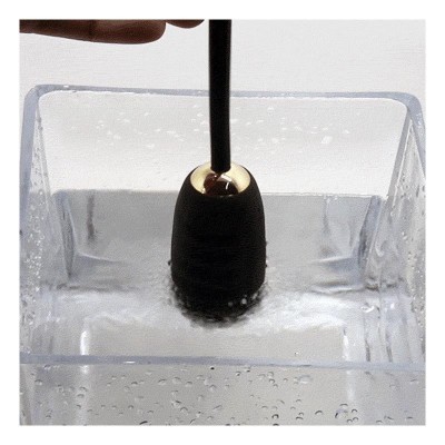 Acessório preto com detalhes dourados numa caixa de água transparente.