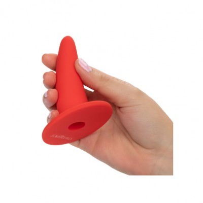 Plugue anal vermelho de silicone segurado por uma mão, fundo branco