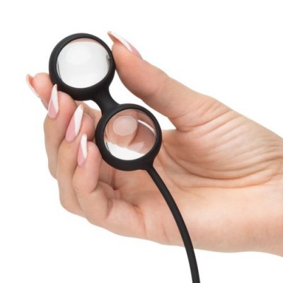 Lupa com duas lentes circulares em estrutura preta, segurada por uma mão com unhas decoradas