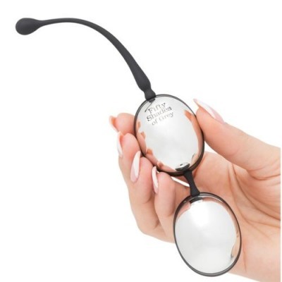 Acessório oval em metal e silicone preto com texto Fairy Shaking of things, segurado por mão feminina