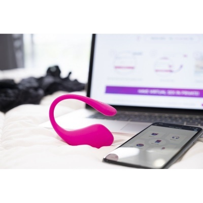 Produto eletrônico rosa ao lado de smartphone e portátil em superfície branca