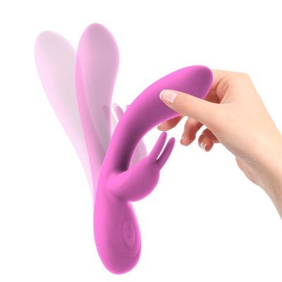 Vibrador rosa de silicone flexível com pêlo de coelho segurado por uma mão