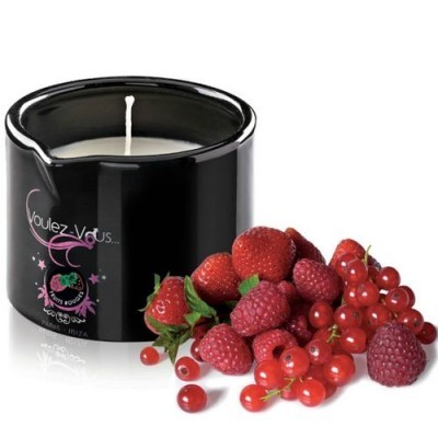 Vela branca em recipiente preto com fruta vermelha fresca ao lado